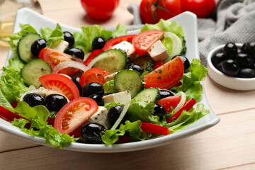Delicious fresh Greek salad on white wooden table, closeup