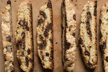 Overhead view of chocolate chip biscotti on a chopping board, top view of chocolate chip cantucci cookies on a brown board, flatlay of slices of biscotti cookies or twice baked cookies