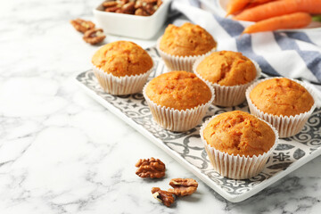 Tasty carrot muffins and walnuts on white marble table, closeup. Space for text