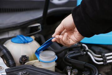 Man opening car windshield washer reservoir, closeup