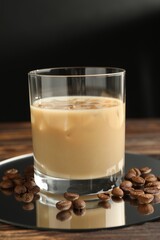 Coffee cream liqueur in glass and beans on wooden table, closeup