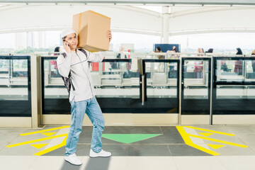 Young Muslim Man Talking on the Phone While Carrying a Box at a Public Transportation Station