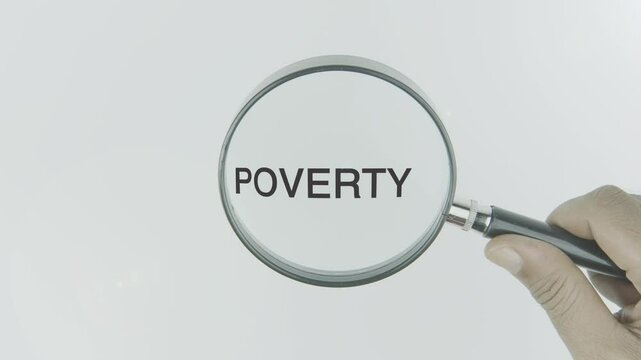 Poverty text or word highlighted by a magnifying glass in a hand on a white background, symbolizing focus on economic hardship, lack of resources, and the struggle for basic needs and equality