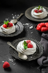 pavlova meringue dessert with raspberries and cream on a black background