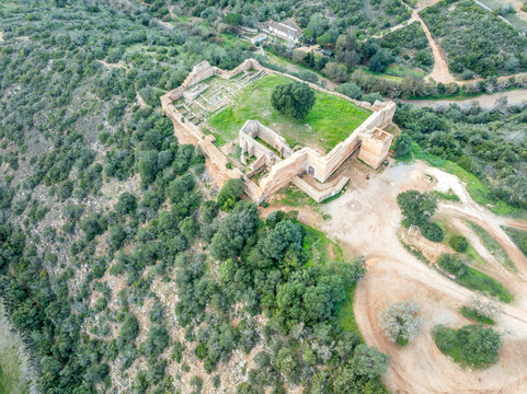 Stone ramparts & crenellated walls define Paderne Castle's medieval architecture, a historic Portuguese fortress against a blue sky