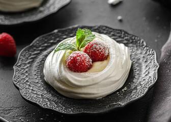 pavlova meringue dessert with raspberries and cream on a black background