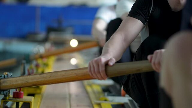 Water sports rowing simulator. Close up rowing team hands work with paddles, preparing for competitions. Arms make circular motions developing flexibility stability, muscle memory and concentration