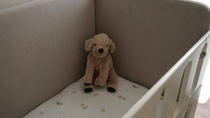Soft plush dog toy sitting alone in a baby crib, evoking warmth and nostalgia