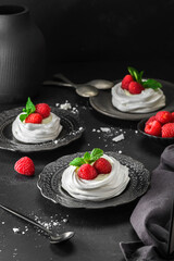 pavlova meringue dessert with raspberries and cream on a black background