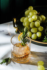 a glass of whiskey decorated with lemon and rosemary