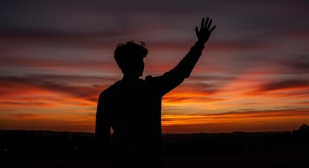 Fototapeta premium Silhouette of a person waving against a colorful sunset 