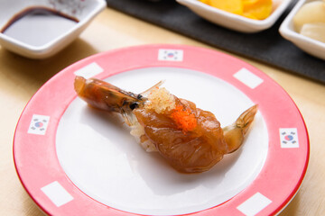 Raw shrimp sushi marinated in soy sauce and topped with flying fish roe
