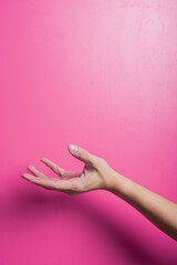 Asian hand in an open palm gesture facing upward against a pink background, symbolizing giving, receiving, offering help, asking, or support in a clean and simple studio setup.