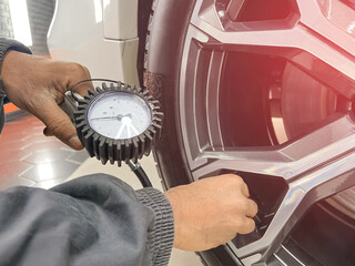Tire pump inflating car wheel. Tyre inflator in man hands with manometer. Hand car mechanic holding...