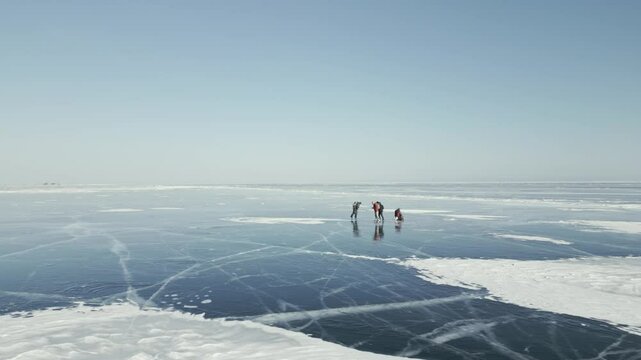 Tourists with a backpack is skating on the blue transparent ice of the endless lake Baikal. The concept of unique winter places of the earth