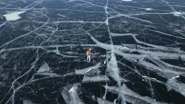 Tourists with a backpack is skating on the blue transparent ice of the endless lake Baikal. The concept of unique winter places of the earth