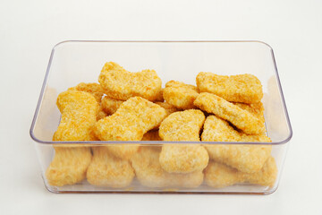 Homemade raw fried chicken nuggets on food container, frozen food preparation 
