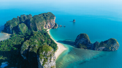 An aerial vista reveals the breathtaking beauty of Railay Beach in Krabi, Thailand, where emerald waters lap at golden shores, surrounded by dramatic limestone cliffs and vibrant greenery.