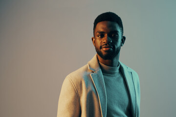 Obraz premium Stylish African man in elegant attire, conveying confidence against a cool toned background, perfect for concepts of fashion and modern masculinity