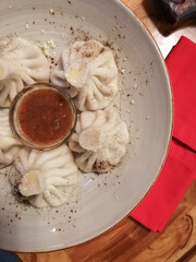 Georgian khinkali in a plate with sauce are on the table in a restaurant