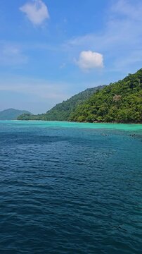 Surin Island in Thailand captivates with its crystal clear waters and lush green hills under a bright blue sky. A perfect day for exploring natures beauty and tranquility by the sea.