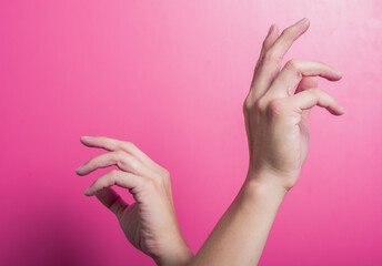 Two Asian hands posed with elegant, curved fingers in a soft, artistic motion against a bright pink background, representing balance, creativity, or expressive hand movement in visual storytelling.