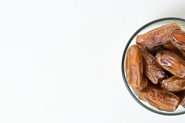 Top view of kurma tunisia or sweet dried dates palm fruits in a little glass bowl. Isolated on white background. clipping path. Half view. Copy space, empty space, free space.
