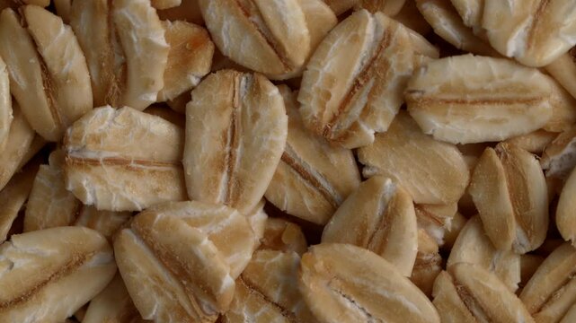 Top view, closeup of a rotating pile of raw rolled oats flakes. Healthy Diet concept