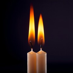 Two lit candles emit warm light in a dark setting creating a calming and serene atmosphere