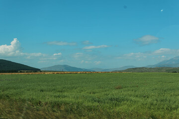 landscape with green field, mountains and clouds
