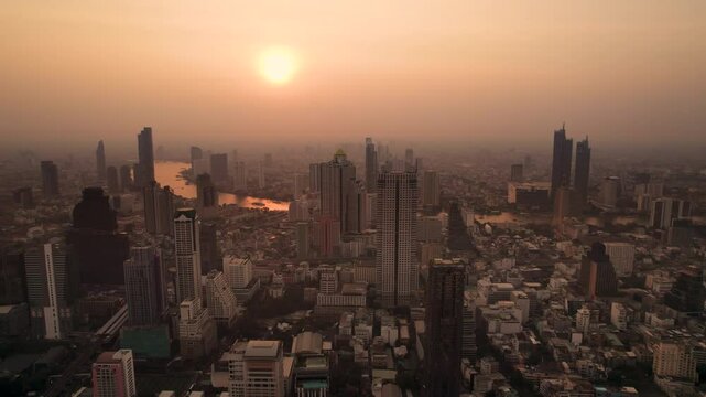 Sunset at Bangkok high aerial view of the Chao Phraya River at Si Lom districts at sunset. A large asian capital city with skyscrapers and millions of inhabitants. Beautiful Cinematic 4k footage 2025