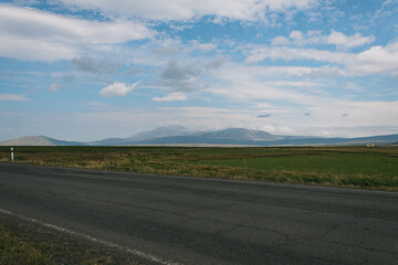 landscape with green field, mountains and clouds