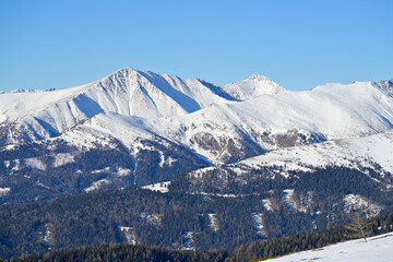 Blue sky above sunny panoramic winter landscape with the summit of mountain Greim in the background. Seen during a hike in the popular Lachtal to the summit Schie&szlig;eck, Styria, Austria