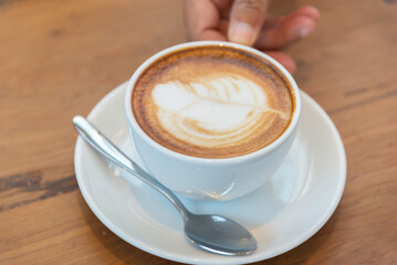 coffee latte art on wood table in cafe nature light