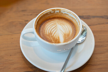 coffee latte art on wood table in cafe nature light