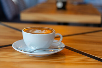 coffee latte art on wood table in cafe nature light