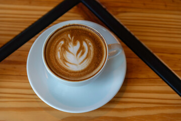 coffee latte art on wood table in cafe nature light