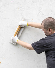 Man is holding a trowel and a putty knife