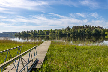 Fototapeta premium A wooden bridge spans a body of water, with a dock on the other side