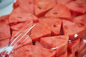 Close-up of chopped ripe watermelon on a plate wrapped with plastic bag