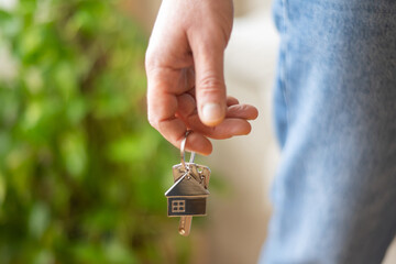 Real estate agent is holding keys with house shaped keychain after signing a contract for a new home, symbolizing property purchase, mortgage approval, and successful real estate transaction