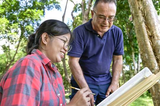 Senior art teacher teaching artist girl to paint in outdoor art class