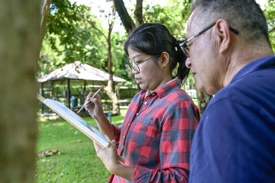 Senior art teacher teaching artist girl to paint in outdoor art class - Powered by Adobe