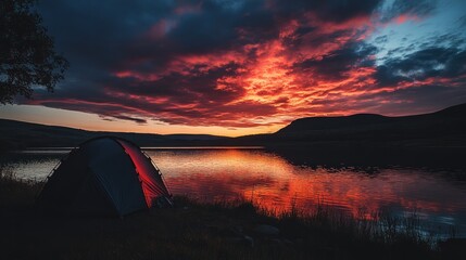 Obraz premium Dramatic sunset over calm lake with tent.