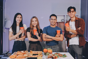 Happy young friends group having lunch at home. Asia family party eating pizza food and laughing enjoying meal while sitting at dining table together at house. Celebration holiday and togetherness.