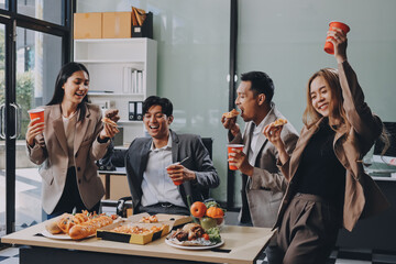 Asian office colleagues and friends enjoy a daytime BBQ with pizza and beer, celebrating Halloween and cheering for their favorite soccer team, creating a lively atmosphere filled with joy.