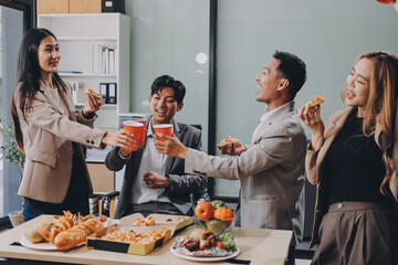 Asian office colleagues and friends enjoy a daytime BBQ with pizza and beer, celebrating Halloween and cheering for their favorite soccer team, creating a lively atmosphere filled with joy.