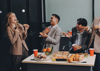 Asian office colleagues and friends enjoy a daytime BBQ with pizza and beer, celebrating Halloween and cheering for their favorite soccer team, creating a lively atmosphere filled with joy.