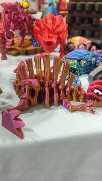 Small ichthyosaurus skeleton printed on 3D printer from molten plastic of pink orange color. Creative multicolored models printed on 3D printer. Concept 3D Printing. 3D Printing technology. Vertical