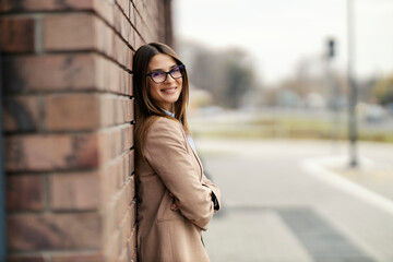 Obraz premium Portrait of confident fashionable lady standing on city street with arms crossed and smiling.